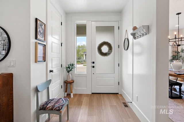 entryway with an inviting chandelier and light wood-type flooring