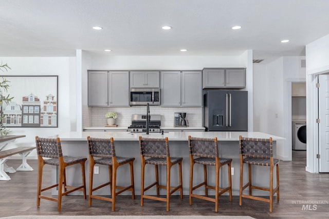 kitchen with gray cabinets, backsplash, stainless steel appliances, and washer / clothes dryer