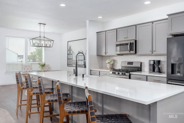 kitchen with a sink, appliances with stainless steel finishes, gray cabinets, and decorative backsplash