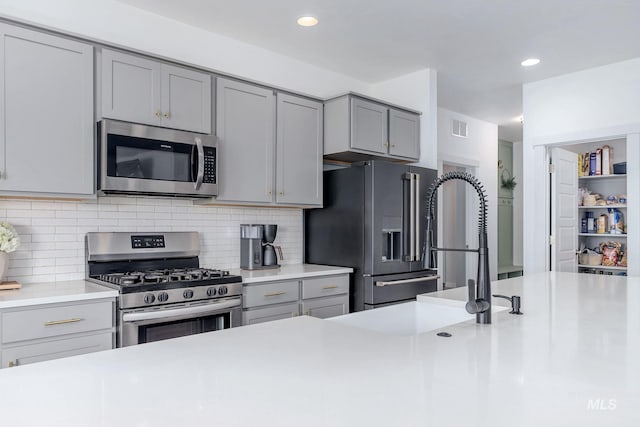 kitchen featuring light countertops, stainless steel appliances, gray cabinetry, and visible vents