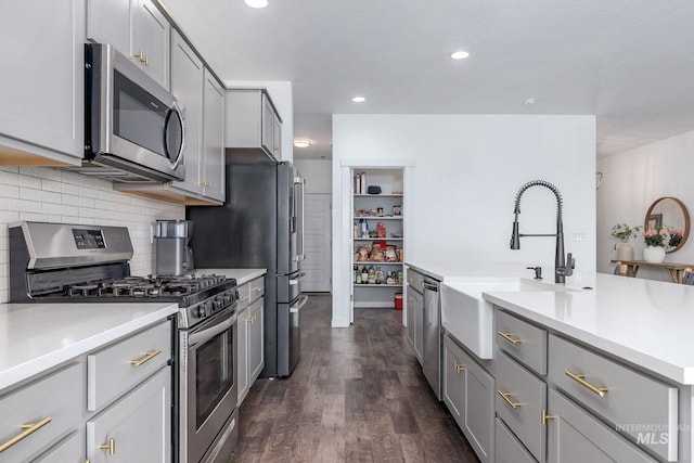 kitchen featuring light countertops, gray cabinets, appliances with stainless steel finishes, and tasteful backsplash