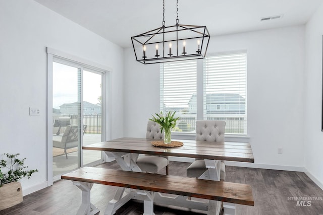 dining area featuring baseboards, visible vents, wood finished floors, and an inviting chandelier