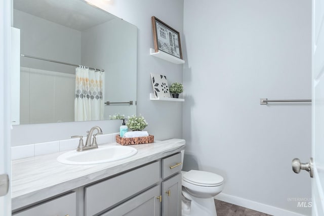 bathroom featuring toilet, baseboards, a shower with curtain, and vanity