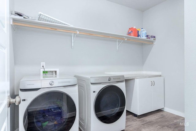 laundry area with laundry area, washer and clothes dryer, light wood finished floors, and baseboards