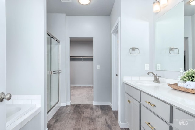 bathroom featuring vanity, a shower stall, wood finished floors, a spacious closet, and a bath