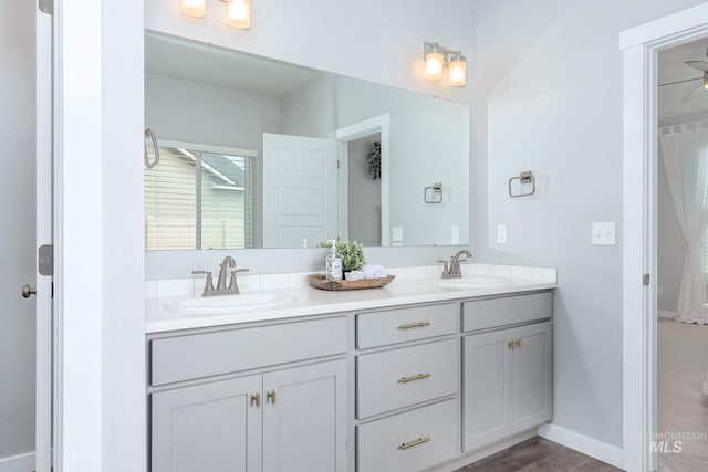 full bath featuring a sink, baseboards, and double vanity