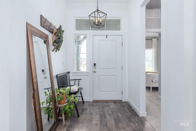 entryway with baseboards, visible vents, dark wood-style flooring, and a notable chandelier