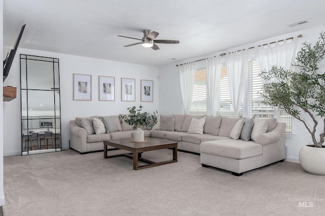 living area featuring a ceiling fan, visible vents, and carpet