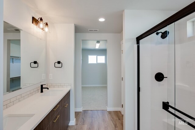 bathroom with a sink, wood finished floors, visible vents, and a stall shower