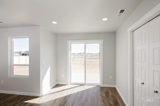 interior space with baseboards, wood finished floors, access to exterior, and visible vents