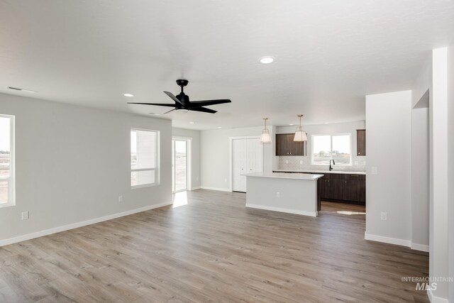 unfurnished living room featuring a sink, light wood-type flooring, ceiling fan, baseboards, and recessed lighting