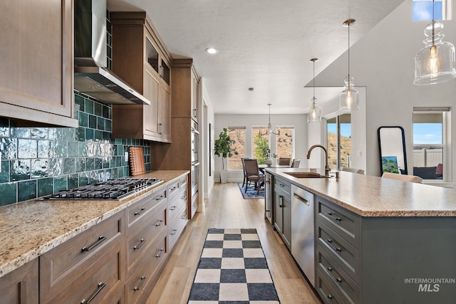 6071 S Pioneer Trail Way, Meridian, ID 83642 - kitchen featuring wall chimney exhaust hood, appliances with stainless steel finishes, light wood finished floors, decorative backsplash, and pendant lighting