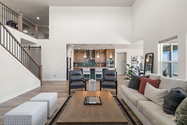 6071 S Pioneer Trail Way, Meridian, ID 83642 - living room featuring a high ceiling, a barn door, light wood-type flooring, recessed lighting, and stairs