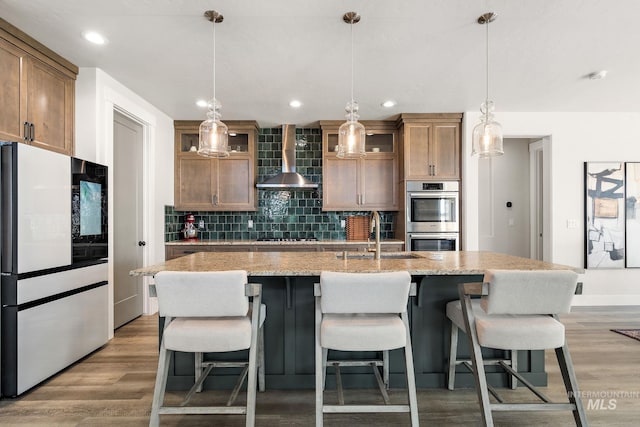 6071 S Pioneer Trail Way, Meridian, ID 83642 - kitchen with appliances with stainless steel finishes, wall chimney exhaust hood, decorative backsplash, light wood-style floors, and recessed lighting