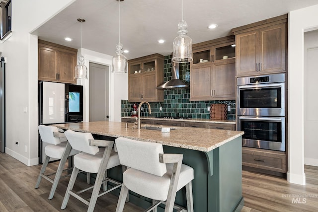 6071 S Pioneer Trail Way, Meridian, ID 83642 - kitchen with stainless steel appliances, wall chimney exhaust hood, backsplash, recessed lighting, and light wood-style flooring