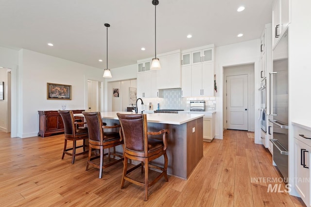 6706 Big Wood Way, Star, ID 83669 - kitchen featuring light wood-style floors, a center island with sink, light countertops, a kitchen breakfast bar, and recessed lighting