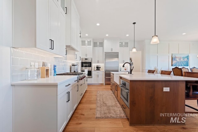 6706 Big Wood Way, Star, ID 83669 - kitchen with a sink, stainless steel appliances, a breakfast bar area, glass insert cabinets, and light wood-style flooring