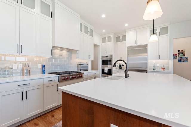 6706 Big Wood Way, Star, ID 83669 - kitchen with stainless steel appliances, a sink, decorative backsplash, light countertops, and hanging light fixtures