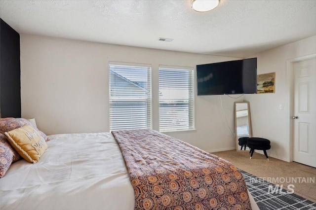 carpeted bedroom featuring a textured ceiling and visible vents