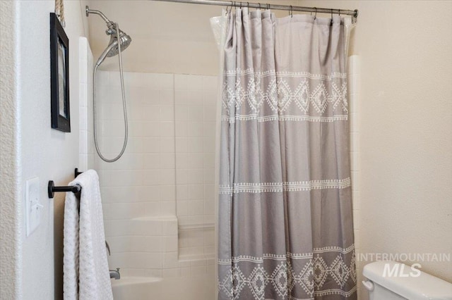 bathroom with shower / bath combination with curtain and toilet