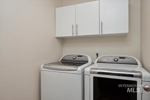 clothes washing area featuring cabinet space and washing machine and clothes dryer