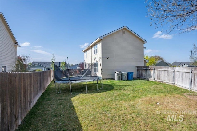 view of yard featuring a residential view, a trampoline, and a fenced backyard