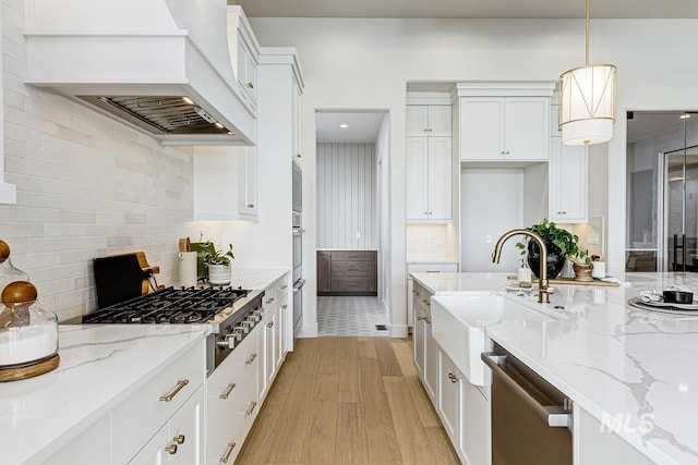 kitchen with backsplash, a sink, white cabinets, light wood-style floors, and stainless steel appliances