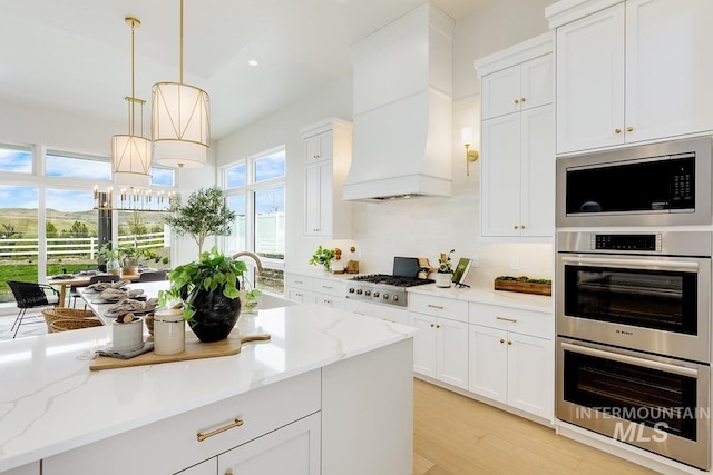 kitchen with double oven, built in microwave, gas stovetop, light wood-type flooring, and custom exhaust hood
