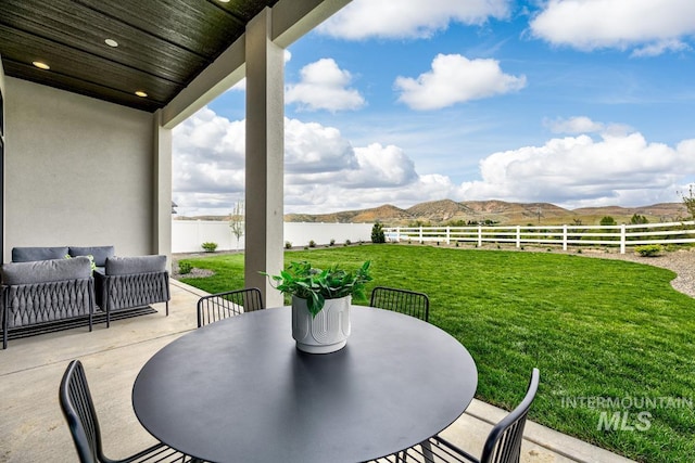 view of patio featuring a fenced backyard, outdoor dining area, a water and mountain view, and outdoor lounge area