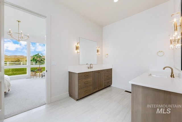 full bathroom featuring ensuite bath, baseboards, a chandelier, and vanity