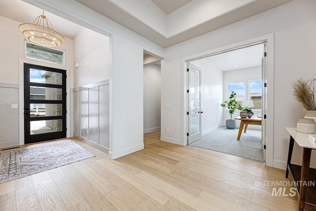 foyer entrance with baseboards, light wood-type flooring, and a chandelier