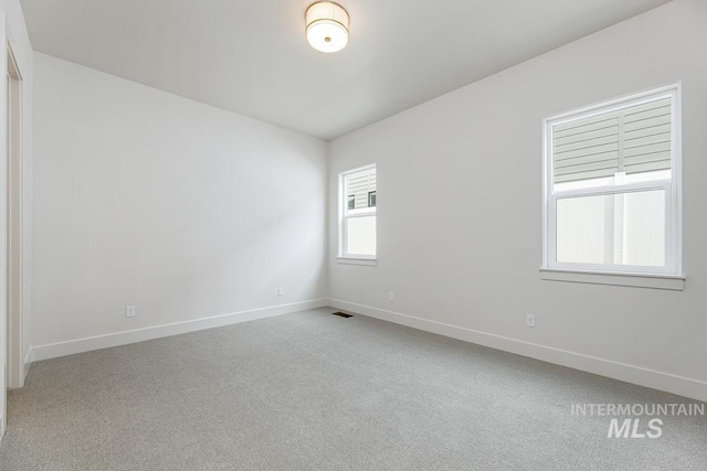 unfurnished room with baseboards, visible vents, and light carpet