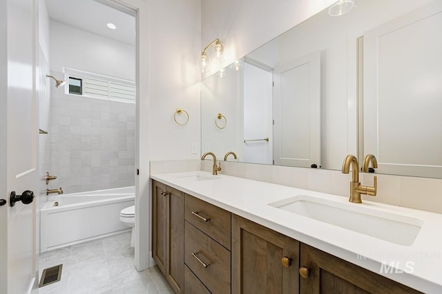 full bath with a sink, toilet, double vanity, and visible vents