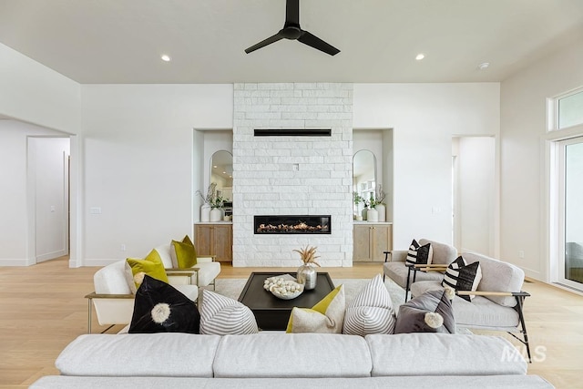 living room with light wood-type flooring, recessed lighting, ceiling fan, and a large fireplace