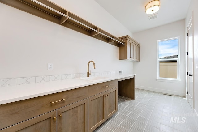 laundry room featuring baseboards, visible vents, and a sink