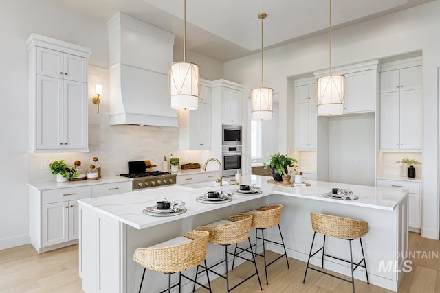 kitchen with a sink, white cabinetry, an island with sink, and tasteful backsplash