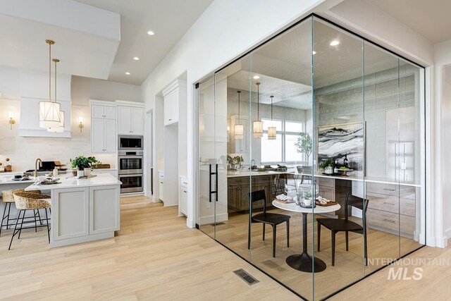 kitchen featuring visible vents, light countertops, white cabinetry, light wood finished floors, and appliances with stainless steel finishes