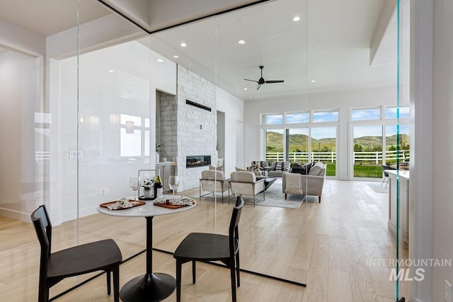dining area with a stone fireplace, recessed lighting, ceiling fan, and light wood-type flooring