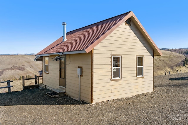 view of home's exterior with entry steps, fence, metal roof, and an outbuilding