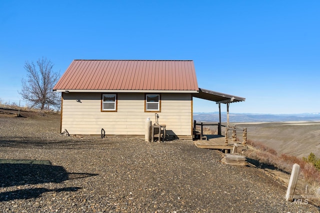 view of property exterior with a mountain view, metal roof, and an outdoor structure