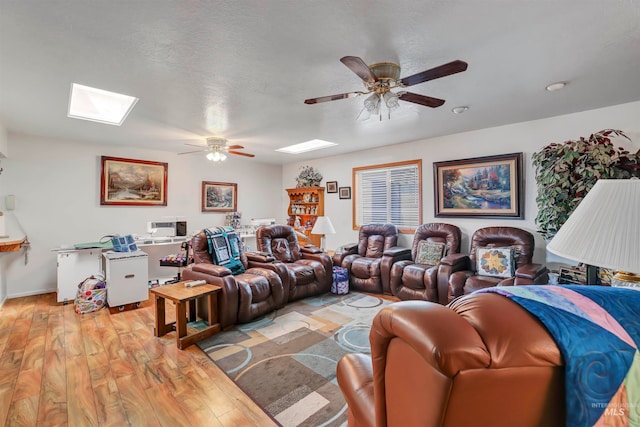 living room featuring a skylight, light hardwood / wood-style flooring, and ceiling fan