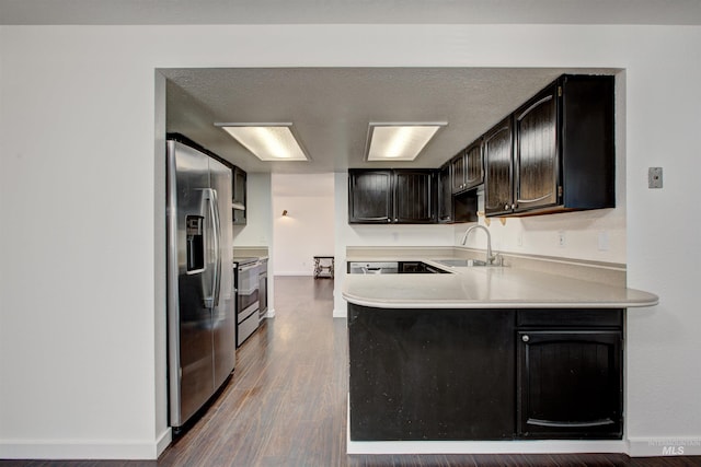 kitchen with kitchen peninsula, sink, appliances with stainless steel finishes, and hardwood / wood-style flooring