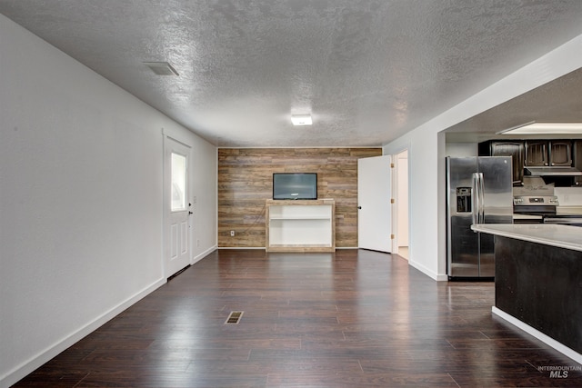 kitchen with dark wood-type flooring, stainless steel appliances, wood walls, and dark brown cabinetry