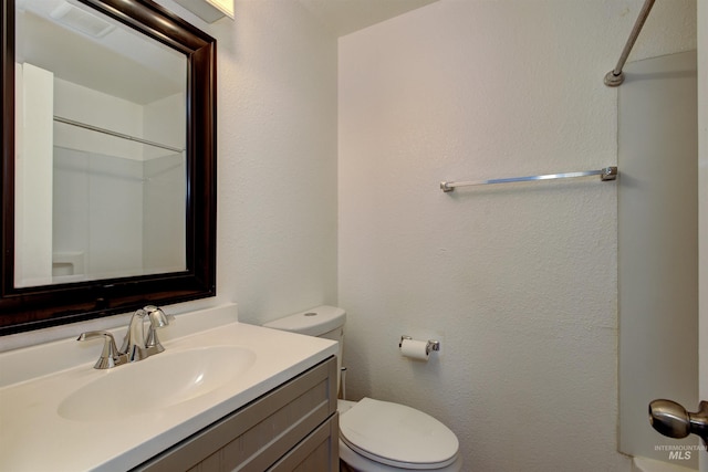 bathroom featuring vanity, toilet, and a shower