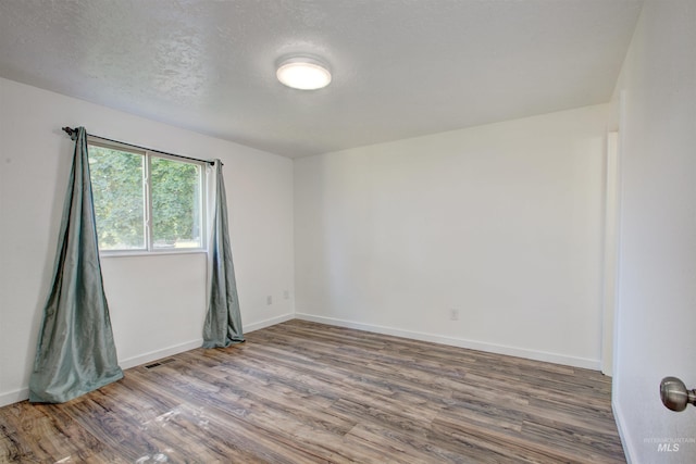 unfurnished room with a textured ceiling and hardwood / wood-style flooring