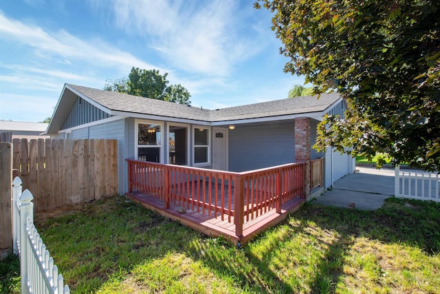 rear view of property featuring a wooden deck and a lawn