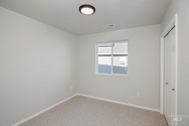 unfurnished room with light colored carpet and a textured ceiling