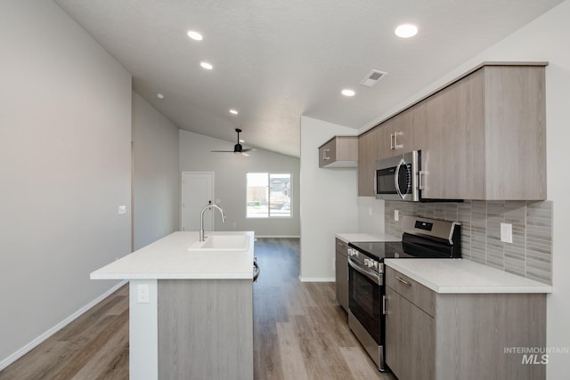 kitchen featuring lofted ceiling, sink, ceiling fan, stainless steel appliances, and an island with sink