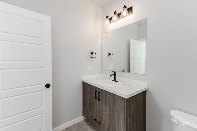 4429 N Magical Creek Ave, Meridian, ID 83646 - bathroom featuring vanity, toilet, baseboards, and wood finished floors