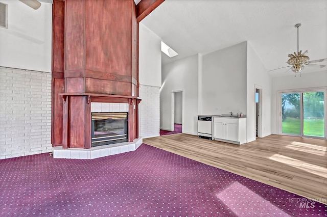 unfurnished living room with ceiling fan, brick wall, light carpet, and a fireplace